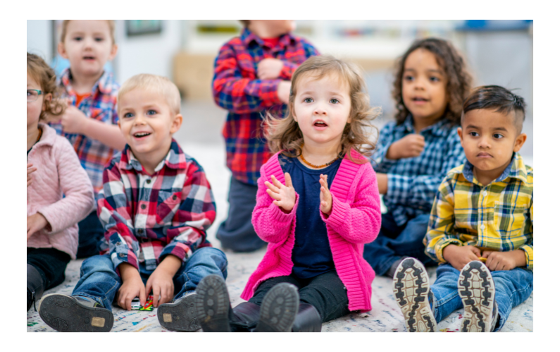 young children sitting on the floor, happy and paying attention.